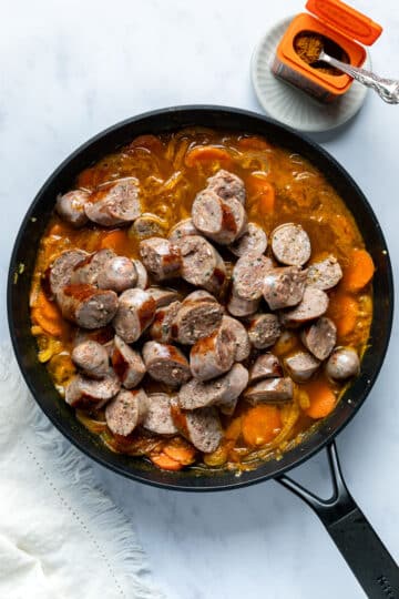 sliced sausages in a pan with curry sauce.