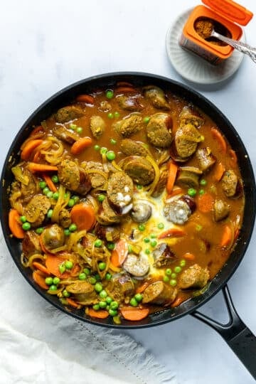 cornflour slurry being added to curry sauce in a pan.