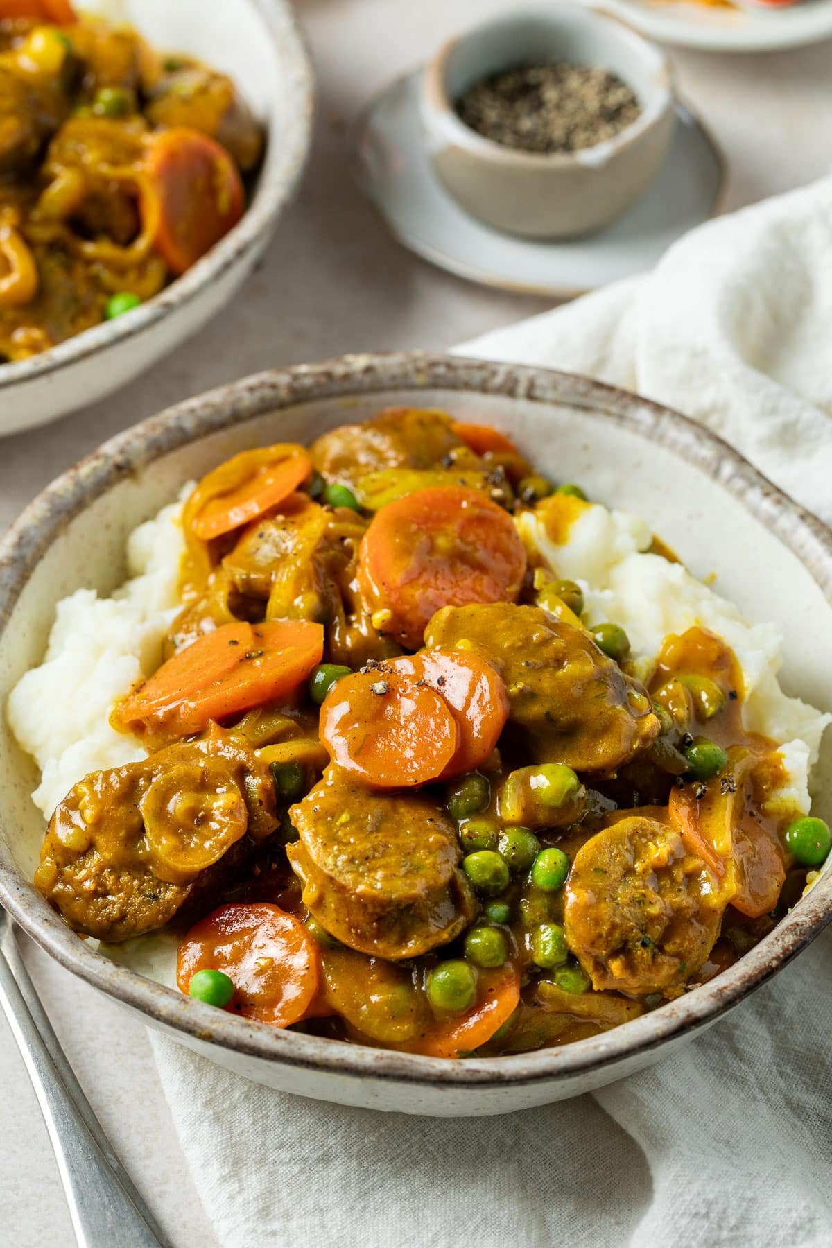 curried sausages in a bowl, over mashed potatoes.