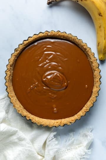 caramel filling poured on top of a biscuit base, in a pie tin.
