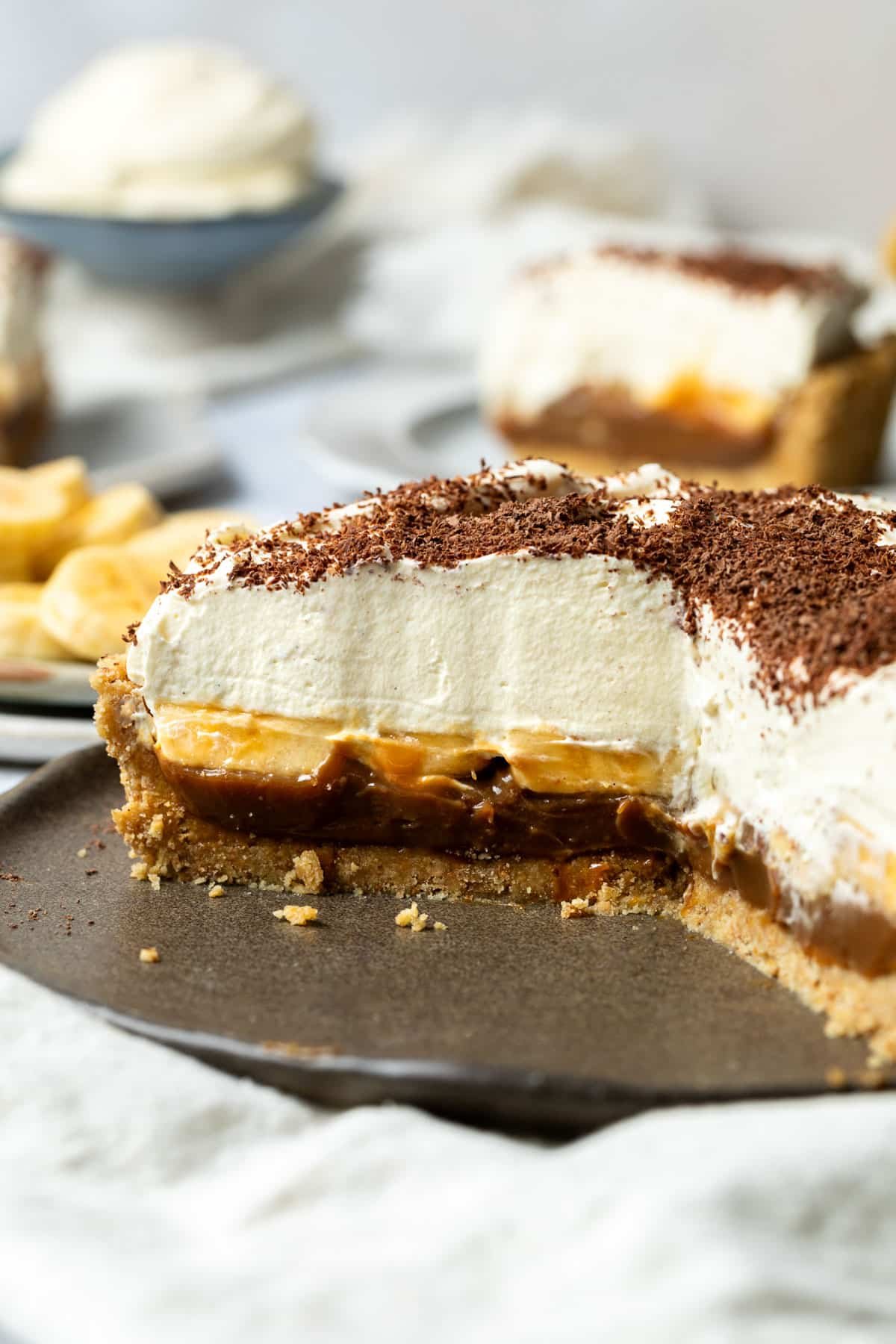banoffee pie, sliced on a large plate. The caramel, banana and cream layers are exposed.