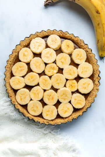 sliced bananas layered over caramel filling in pie base.