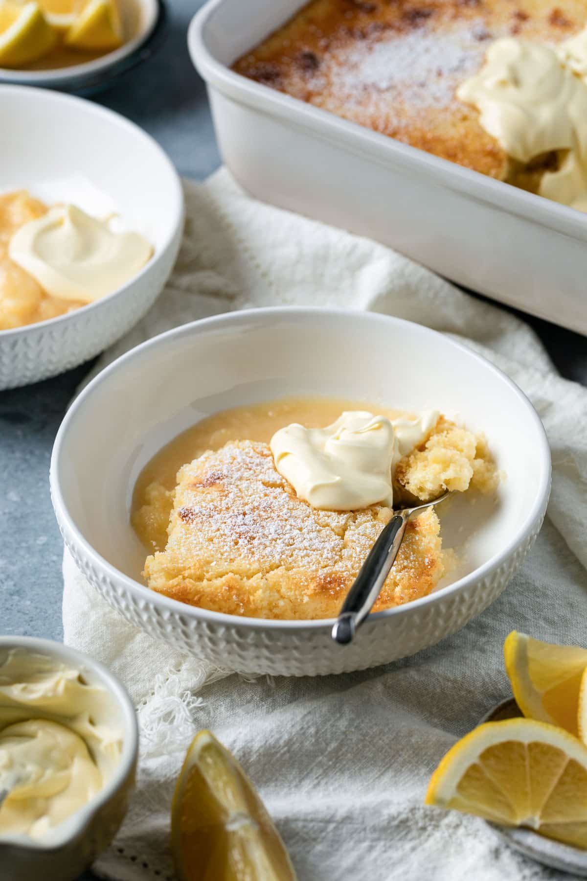a bowl of lemon delicious pudding, topped with a dollop of cream.