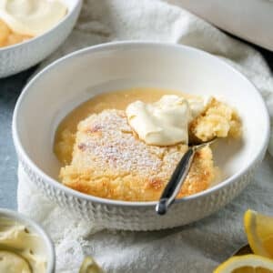 a bowl of lemon delicious pudding, topped with cream.