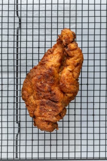 crispy fried chicken resting on a wire rack.