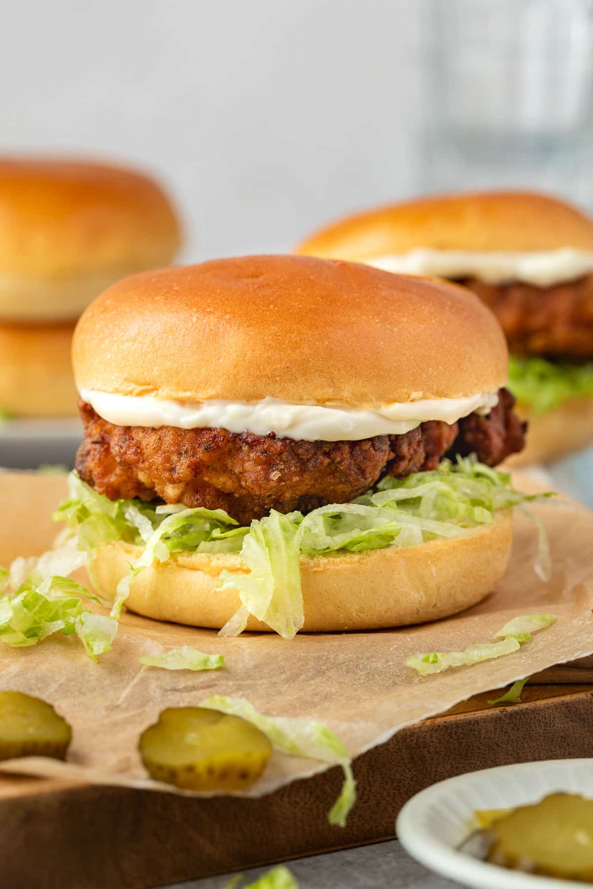 fried chicken burgers on a board with pickles.