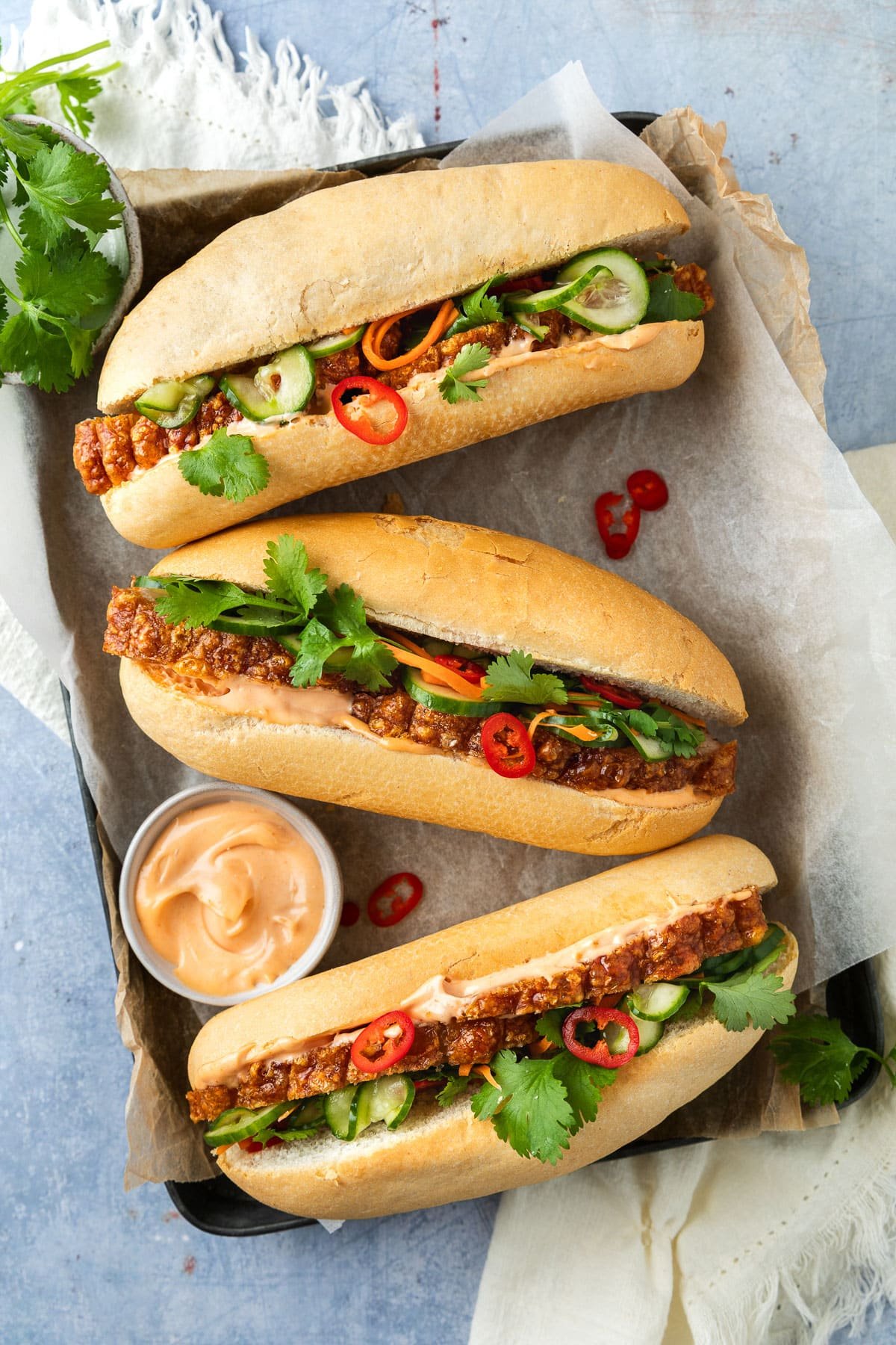 finished pork rolls on a tray, topped with chilli and fresh herbs.