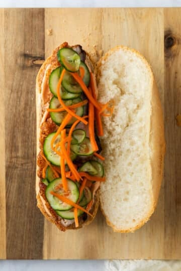 pork and pickled vegetables arranged on a sliced baguette.