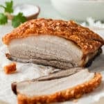 pork belly with crispy skin on a board, with slices of pork.