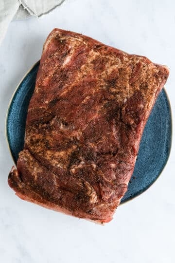 pork belly on a plate. The meat has been covered with spices.
