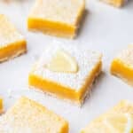 a piece of lemon curd slice topped with icing sugar and a lemon wedge.