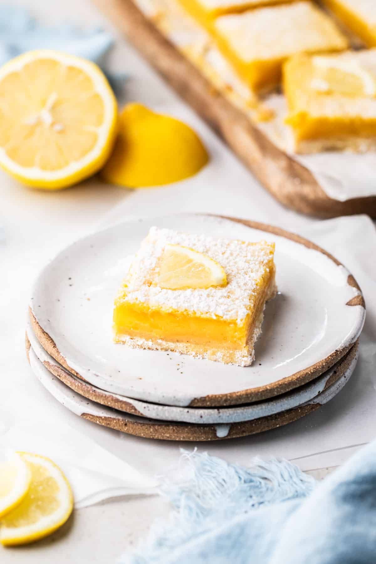 a piece of lemon curd slice on a plate, with lemons.
