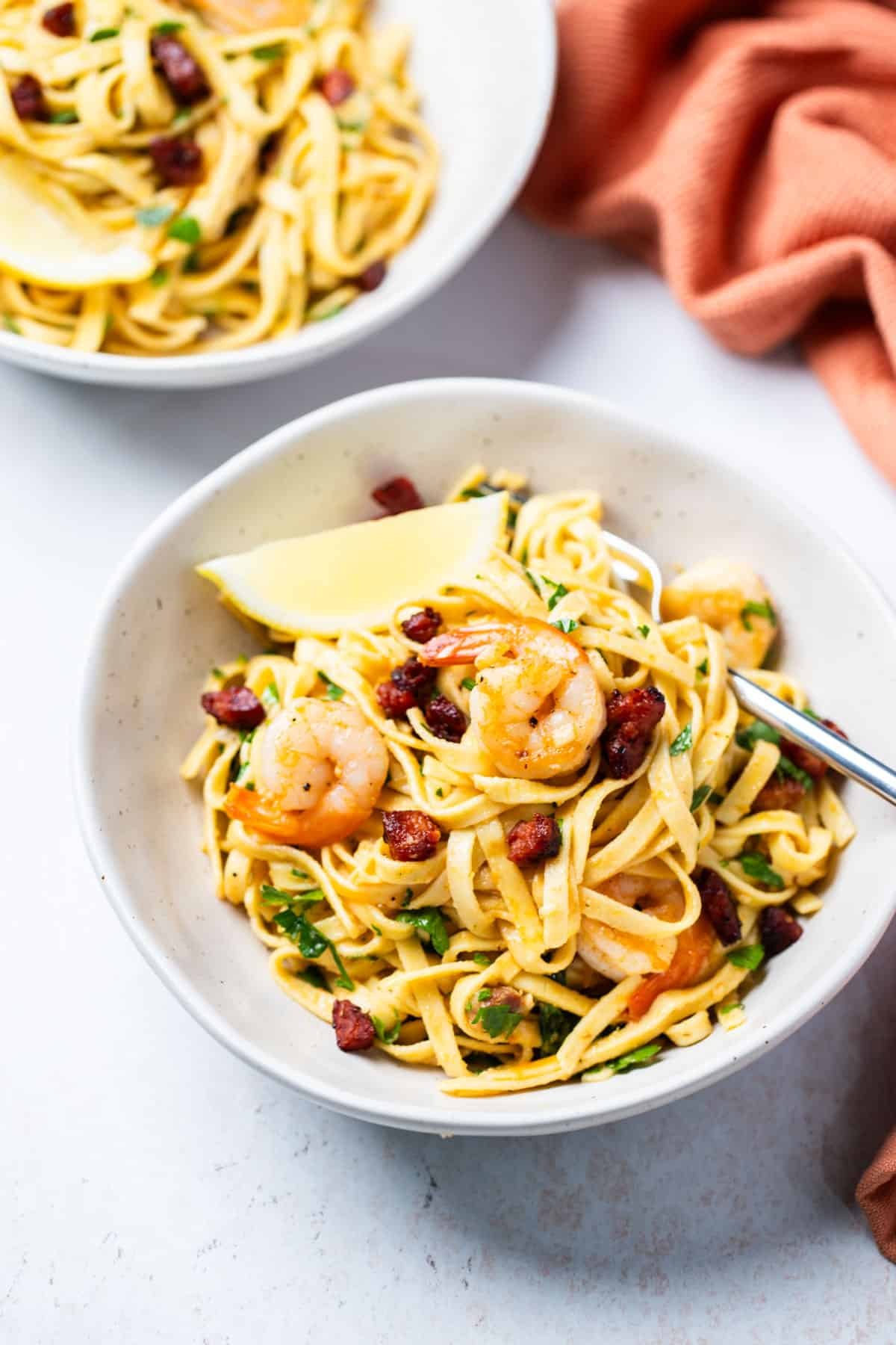 a bowl of prawn and chorizo pasta on a table with a fork.
