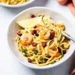 a bowl of chorizo pasta with a lemon wedge on the side.