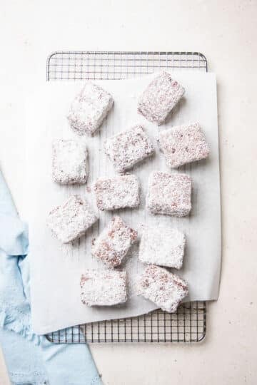 finished lamingtons on a wire rack lined with paper.