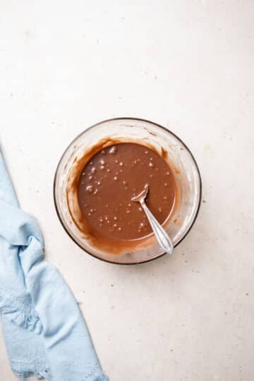 chocolate glaze in a mixing bowl with a spoon.
