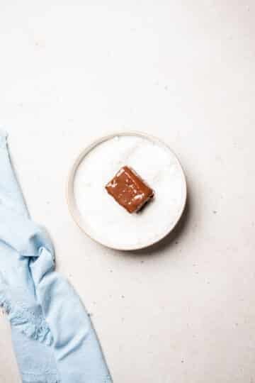 a chocolate-coated cake in a bowl of coconut.