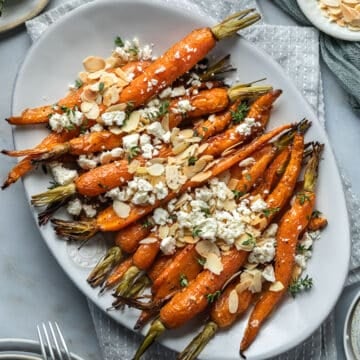 a plate of roasted Dutch carrots, topped with herbs and crumbled feta.