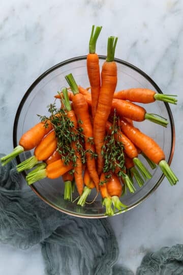Dutch carrots in a bowl with herbs and oil.