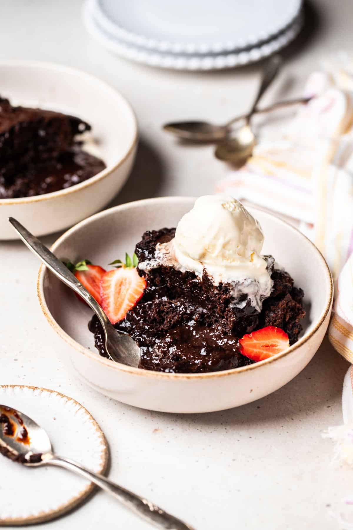 a bowl of self saucing chocolate pudding topped with ice cream and strawberries.